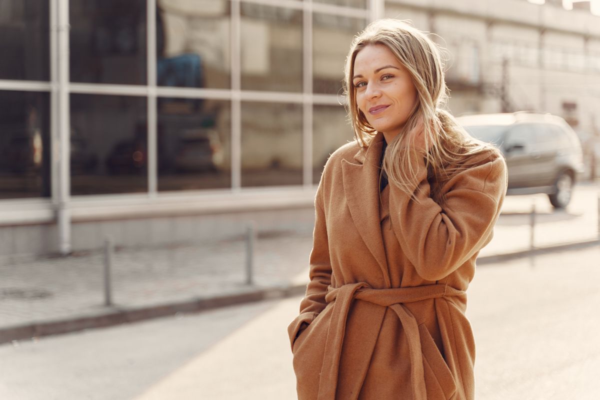 Mujer con abrigo camel caminando por la ciudad