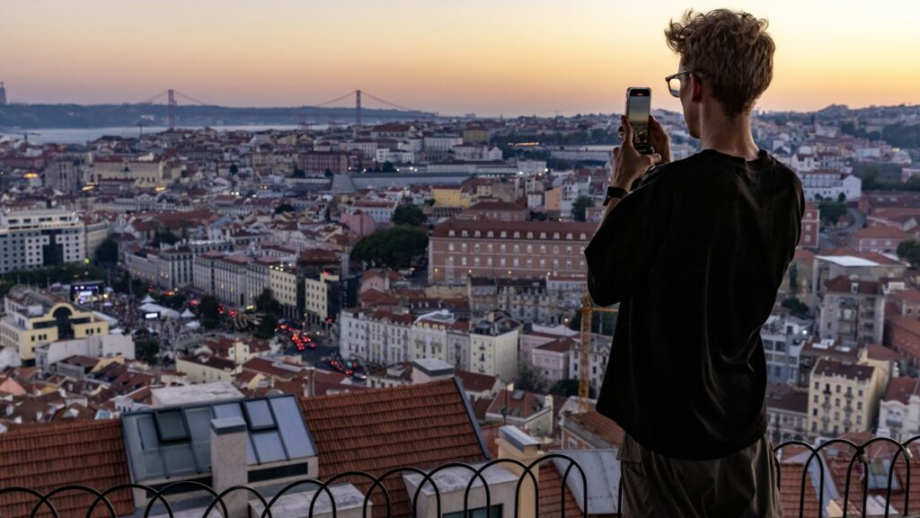 International Roaming Credit on Prepaid Plans for Trips Abroad Traveller photographing Lisbon rooftops at sunset with a phone