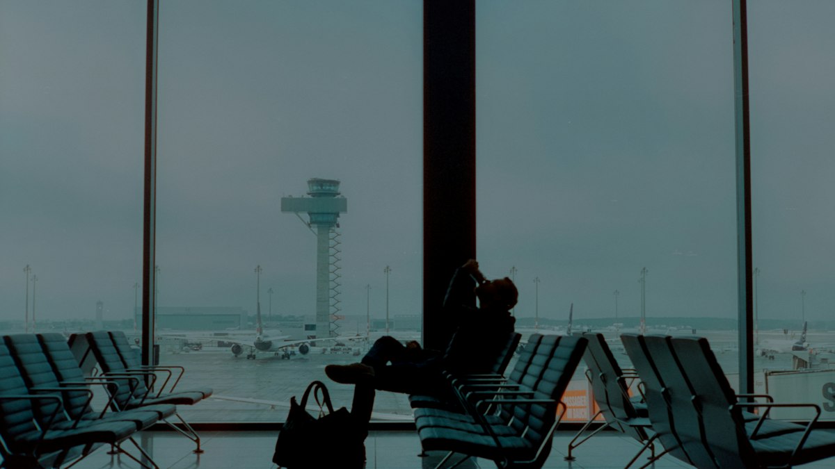 Silhouette of a traveller waiting by an airport window