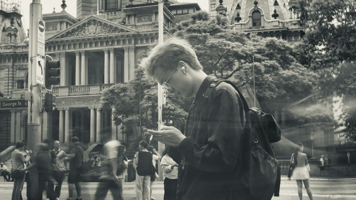 Young man checking his phone on a busy city street