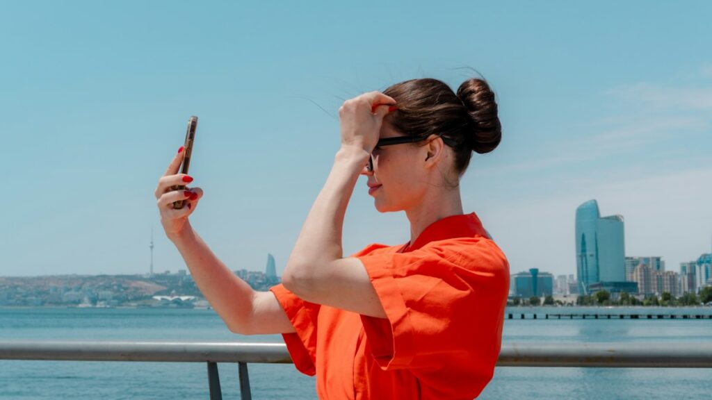 Six Month Prepaid Phone Plans Paid in One Payment Woman in an orange top taking a selfie by a city waterfront