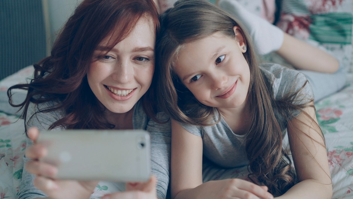 Mother and daughter smiling at a phone together